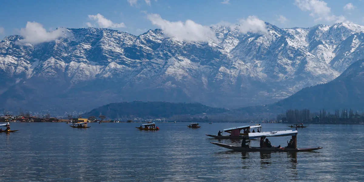 Shikaras on Dal Lake below snow-capped mountains in Kashmir